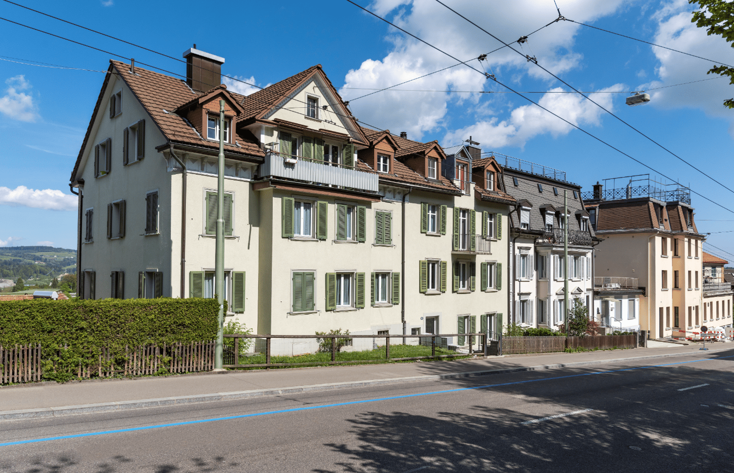 3 story building, brown roof, green shutters, balconies, street view