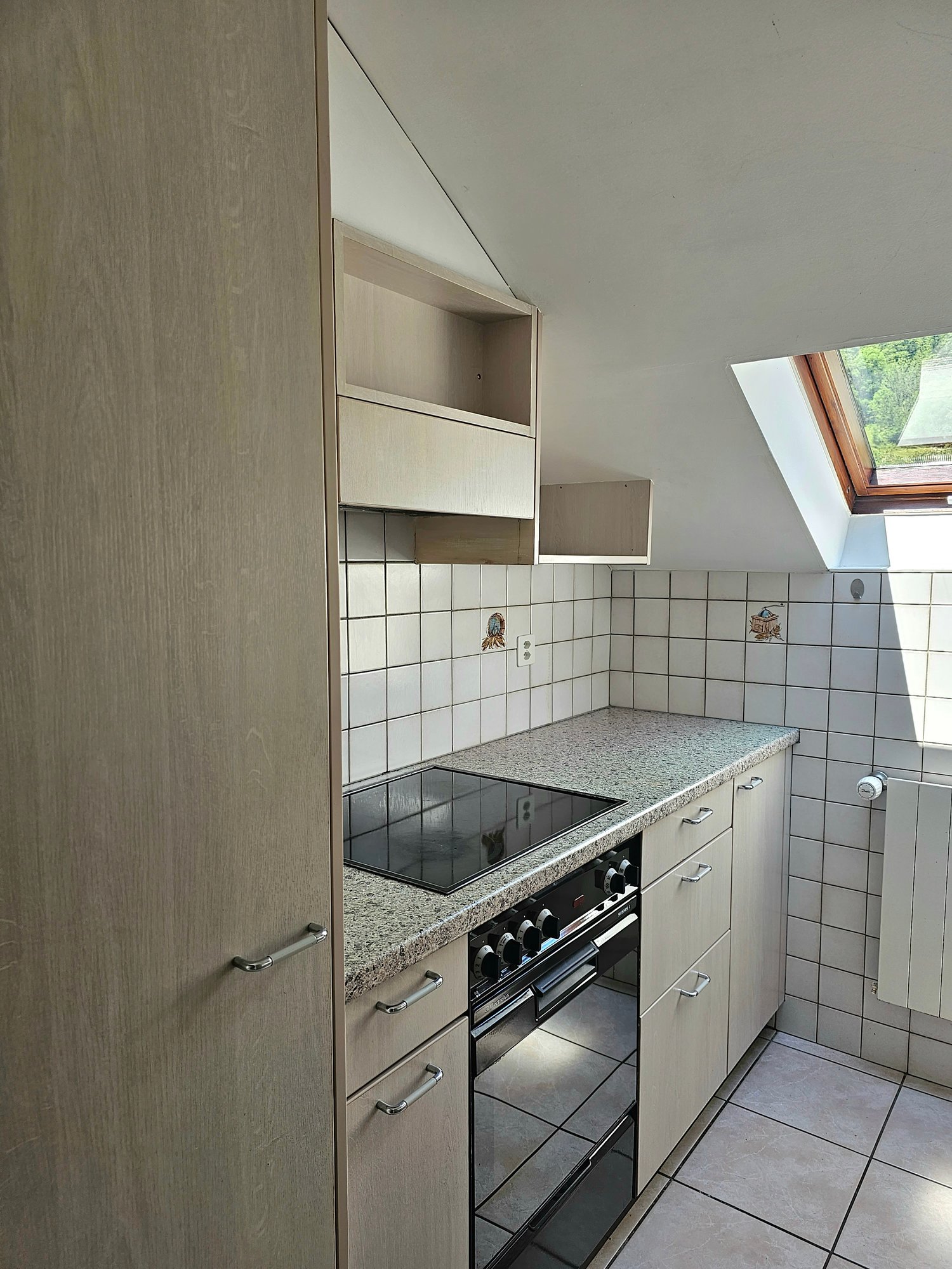 Compact kitchen with built-in cabinets, granite countertop, tiled backsplash, and a built-in oven and stovetop. The kitchen also features a dishwasher.