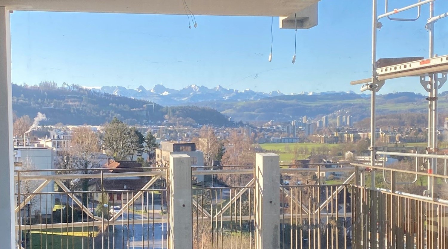 Spacious balcony with a panoramic view of the city skyline and the surrounding mountains. The balcony is equipped with railings and appears to be part of a larger apartment or condominium unit.