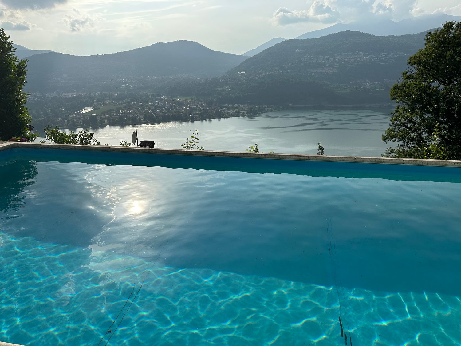 Infinity pool overlooking a scenic lake surrounded by mountains, with clear blue water reflecting the landscape