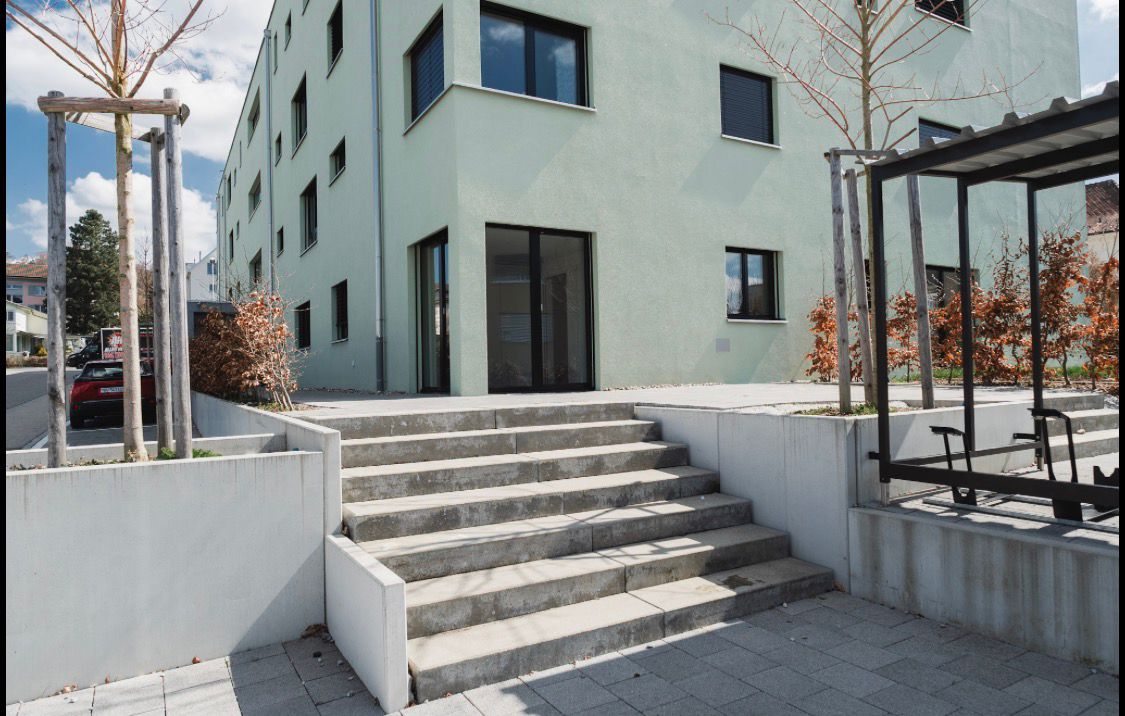3 story building, white exterior, concrete steps, glass doors, windows, concrete walls
