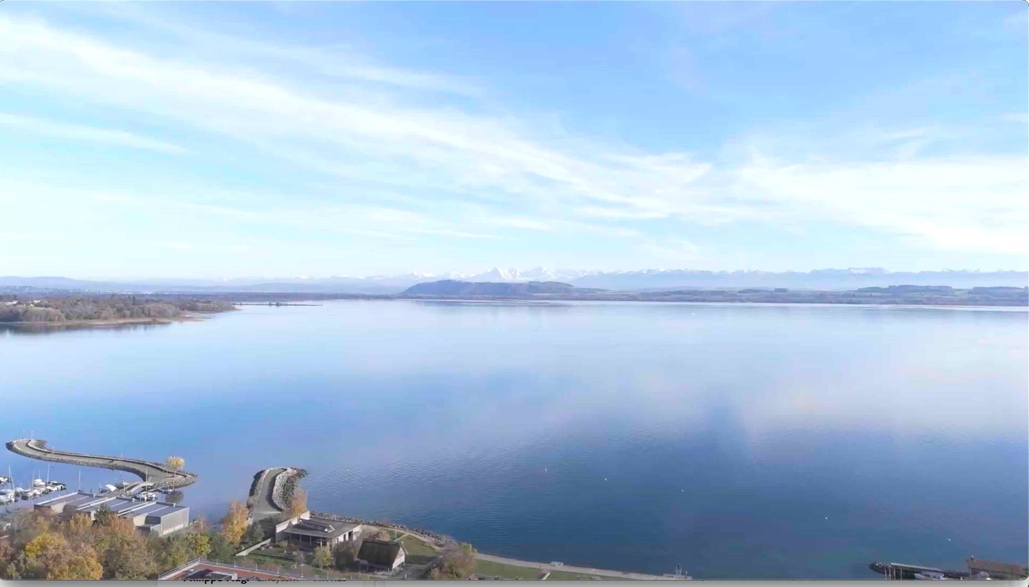 large lake, distant mountains, buildings on the shore