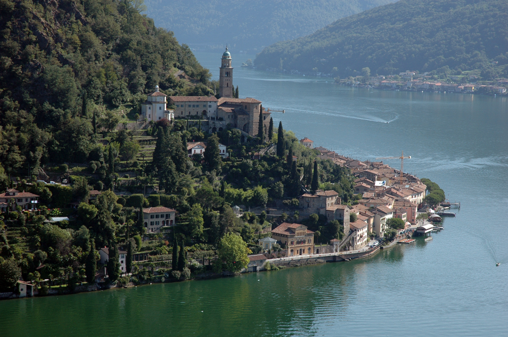 Houses on a hill overlooking a lake, tower, mountains in the background