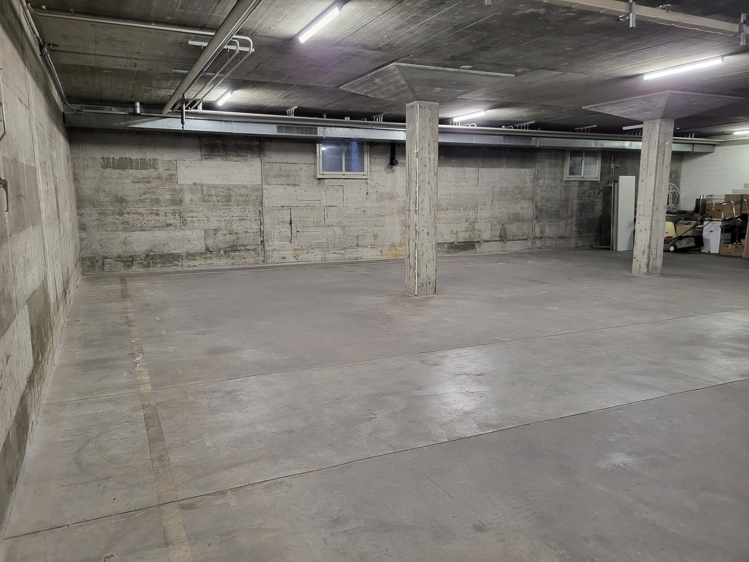 Large empty concrete floor, two pillars, small open window, metal beams