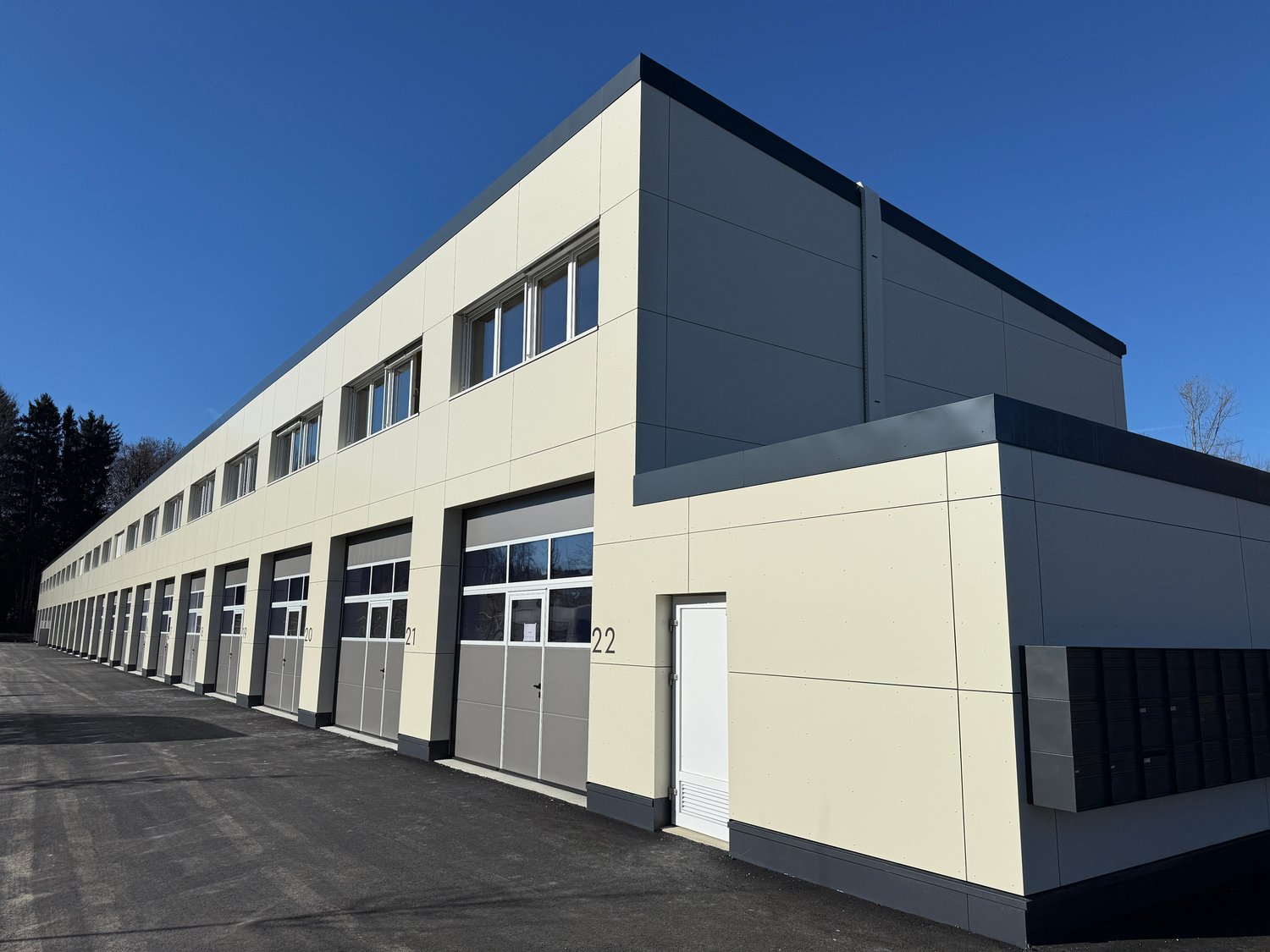 modern building, beige and gray exterior, multiple garages, windows, entrance door