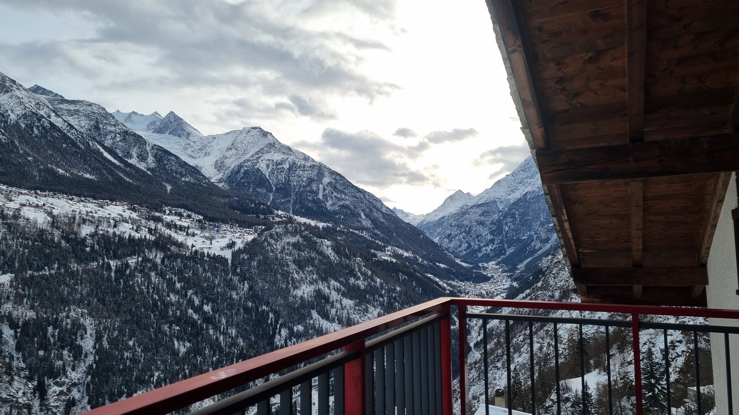 snowy mountains, clear sky, red and black railing, view of village