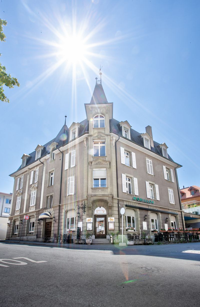 Elegant facade, multiple windows, central entrance, terrace with outdoor seating