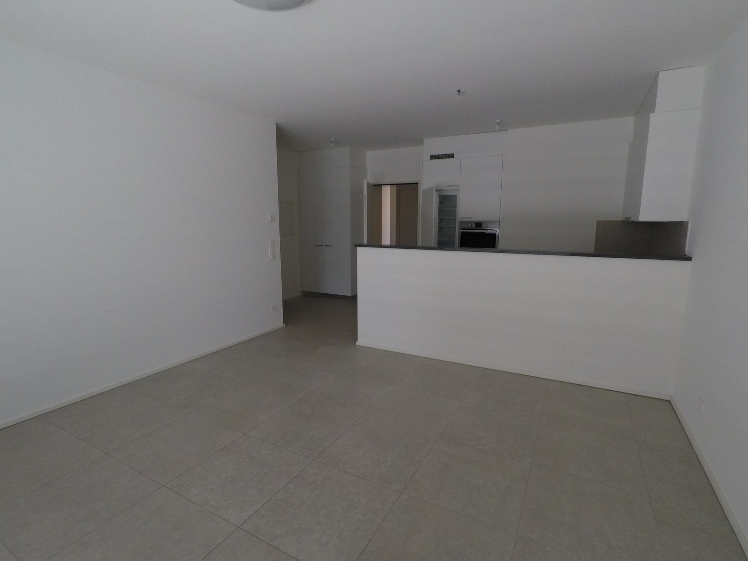 Empty room, tiled floor, kitchen, white walls and ceiling, cupboards, countertop
