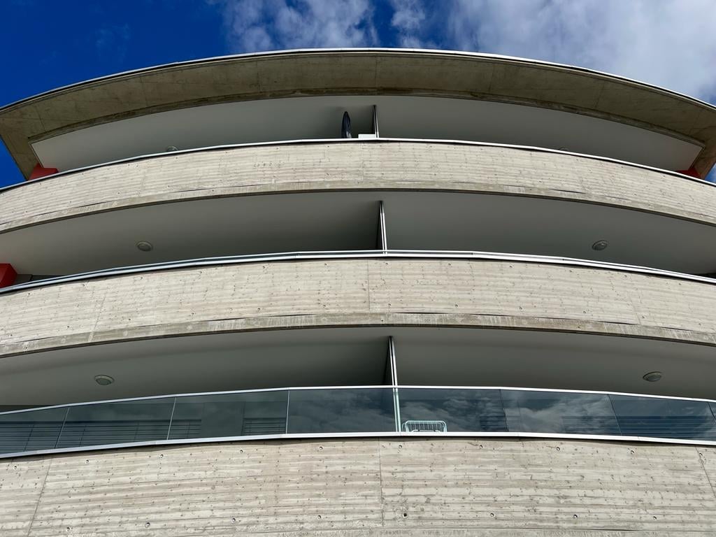 modern design, multiple balconies, curved walls, concrete and glass