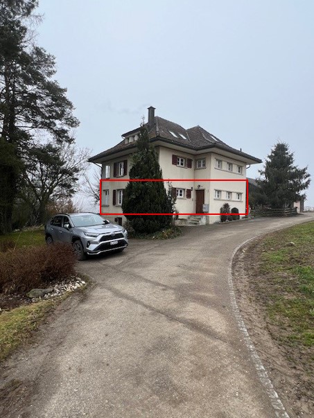 Two story house, white exterior, red roof, multiple windows, car parked in front, trees, grass