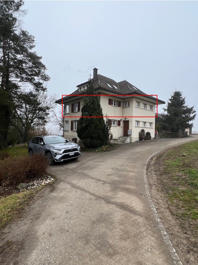 3-story house, beige color, many windows, chimney, paved driveway, a car parked in front