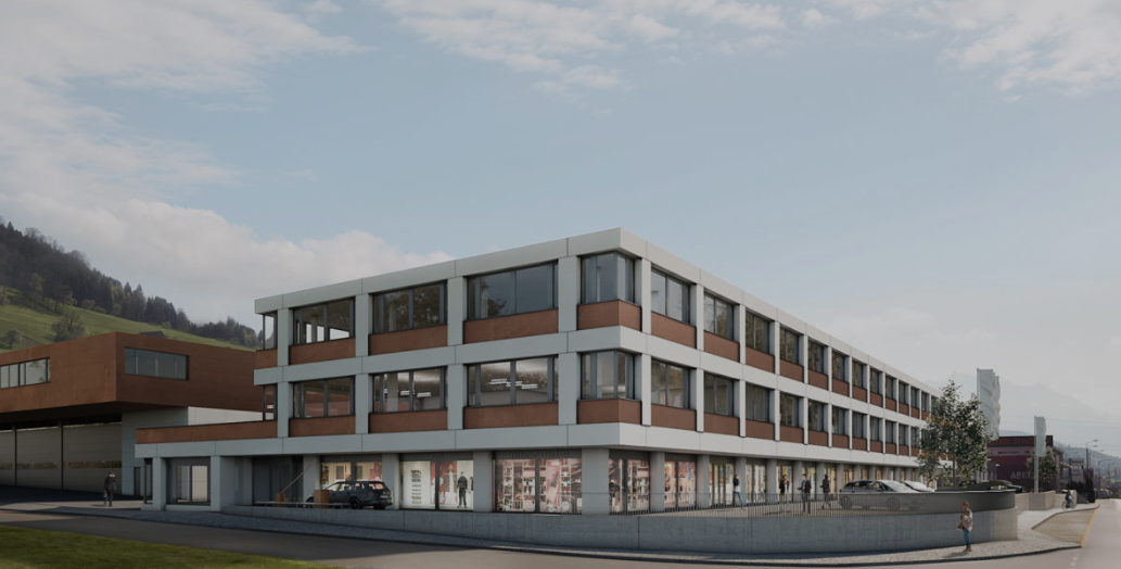 A modern, multi-story commercial building with a mix of glass and brick exterior. The building has multiple floors and appears to have retail or office spaces on the ground level. There is a parking area visible in front of the building.
