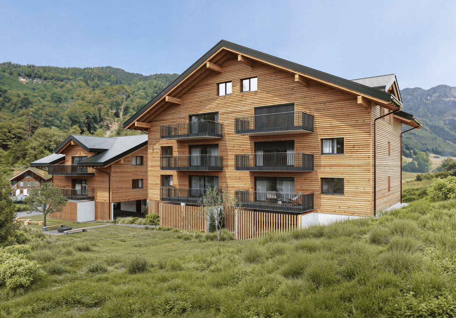 3 story building, wooden exterior, multiple balconies, sloped roof, mountainous surroundings