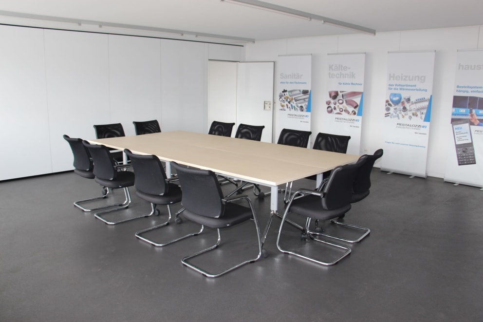 conference room with long table, black chairs, white walls, banners