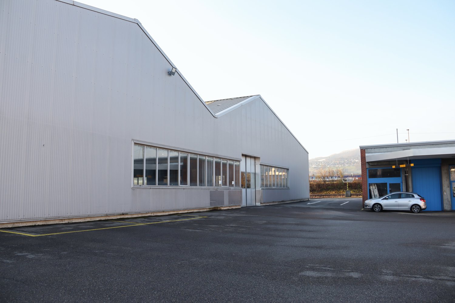 metal siding, large windows, adjacent smaller building, empty parking lot