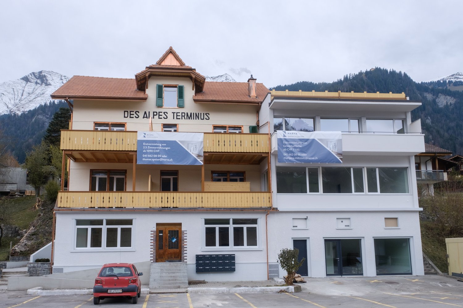 2 story building, brown roof, yellow balconies, white walls, parking lot in front