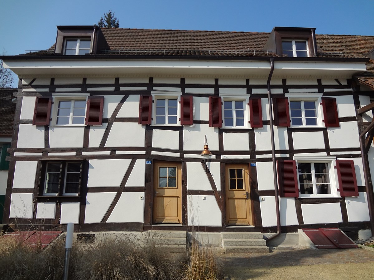 Two story house, white walls, brown trim, red shutters, two doors