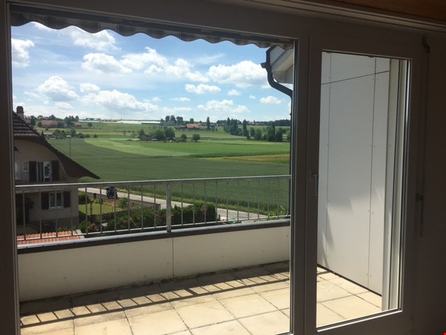 sliding glass door, balcony, metal railing, tiled floor, view of a green field