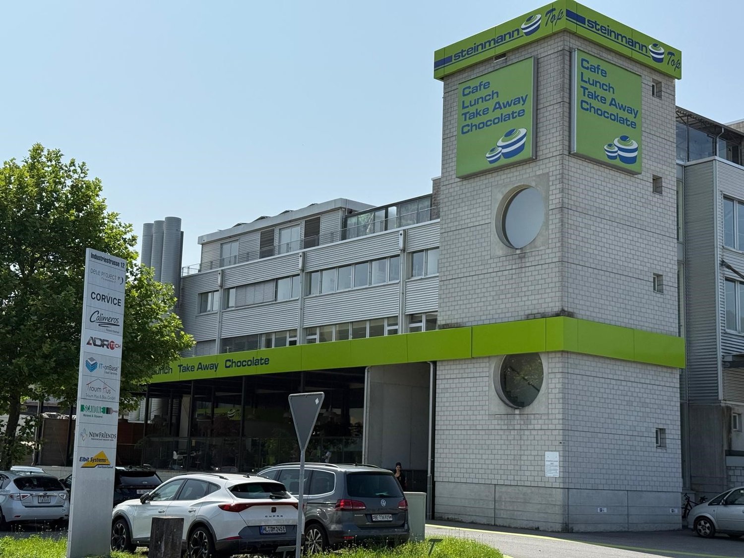 Steinmann Top building with Cafe, Lunch, Take Away Chocolate, multiple windows, cars parked in front