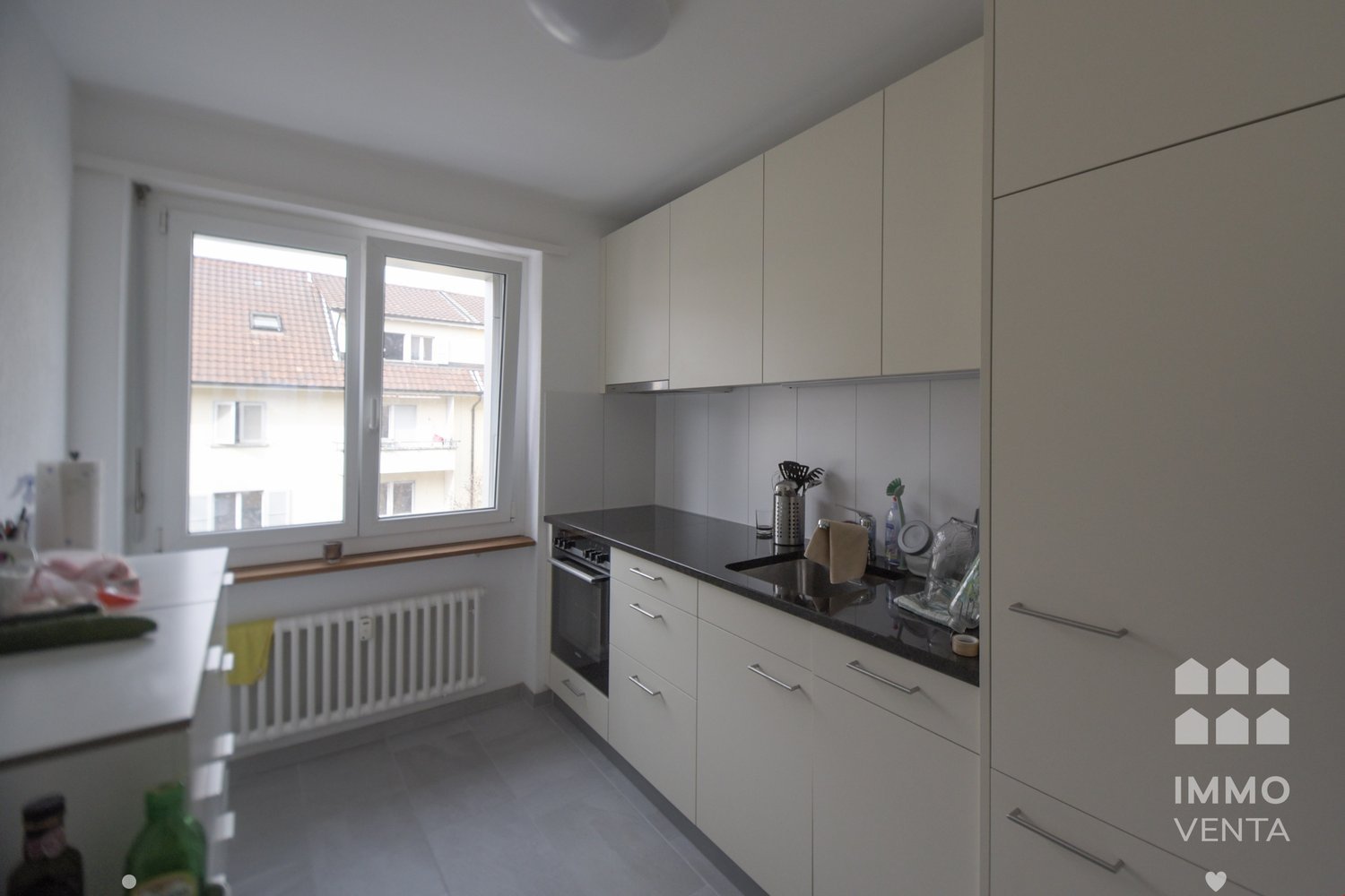 modern white kitchen with gray floor, large window with view, under cabinet sink and dishwasher, built-in oven and dishwasher