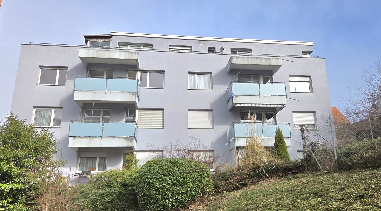 3 story apartment, gray color, glass windows, balconies on every floor