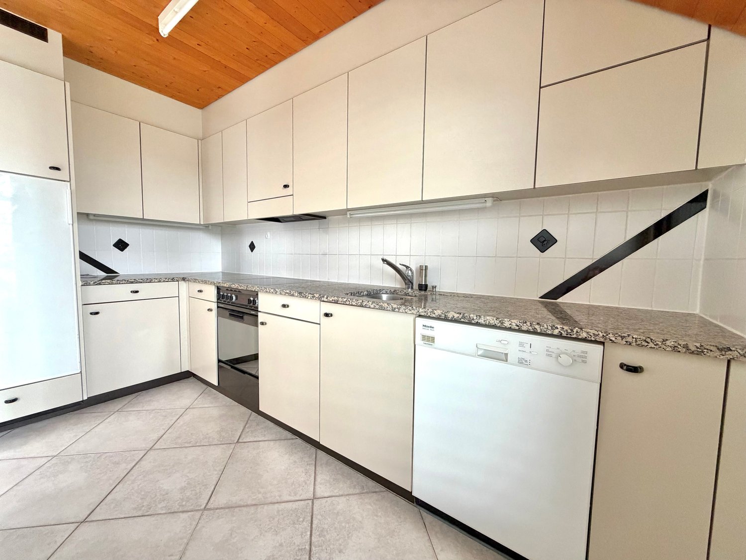 modern kitchen with white cabinets, granite countertops, dishwasher, washing machine, gas stove, wooden ceiling
