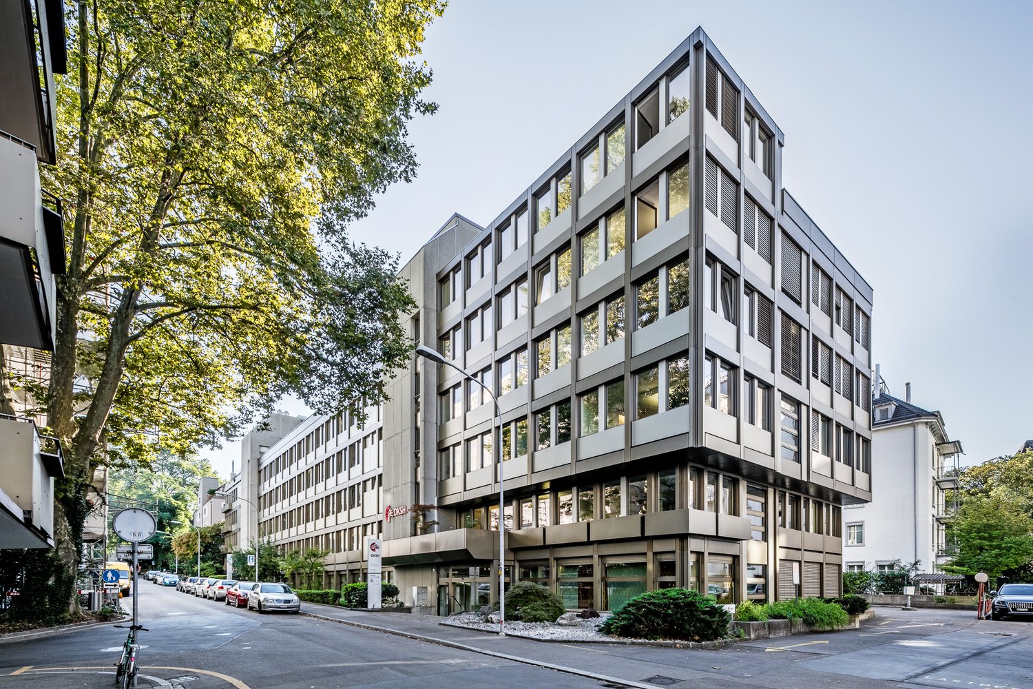 modern, gray, large office building with many windows and raised ground floor
