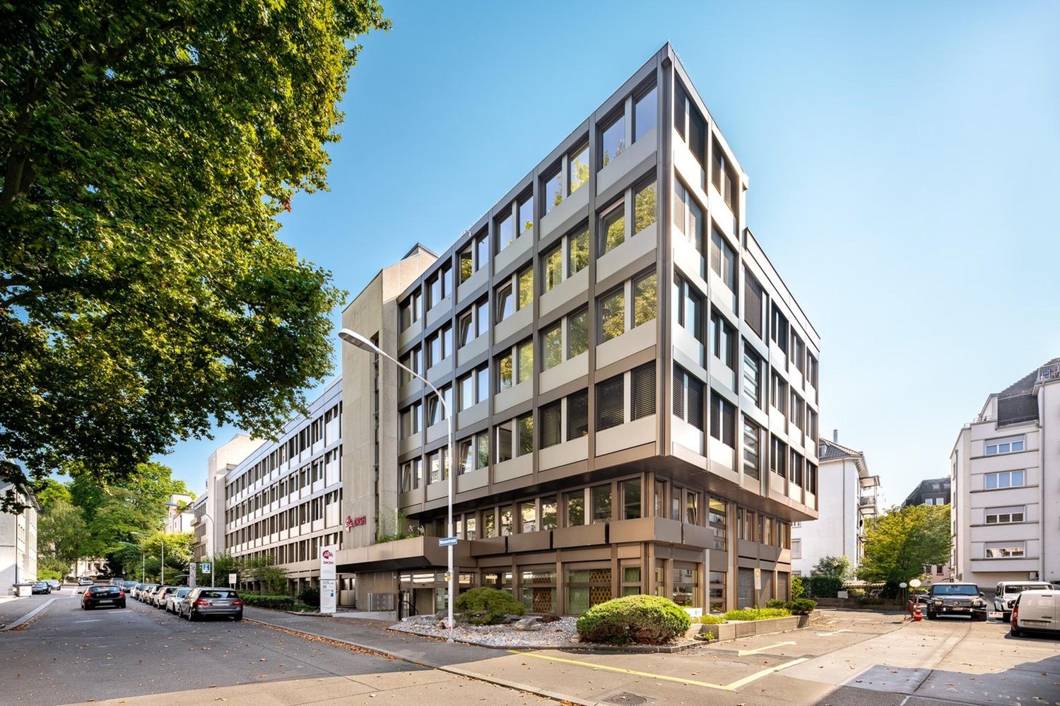 Modern office building with glass facade, multiple floors, and a corner entrance.