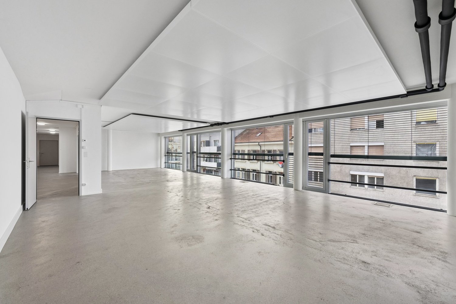 Spacious, clean, white walls, concrete floor, open doors, glass walls, balconies