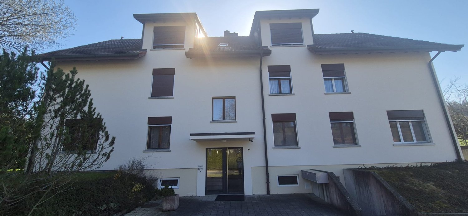 white 2 story building, multiple windows, sloped roof, paved entrance