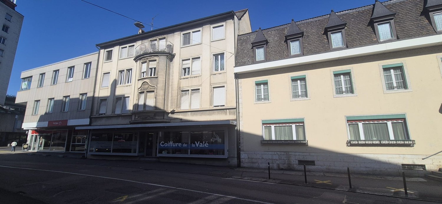 Three story building, white windows, red trims, entrance on street level