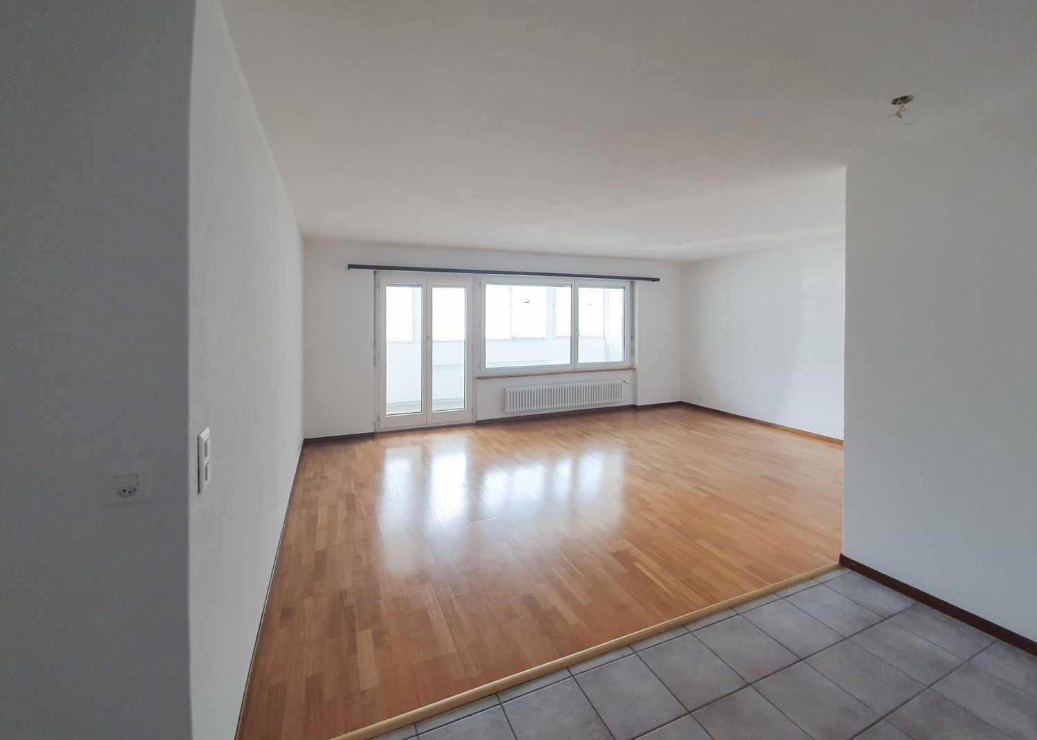 empty room, wooden floor, white walls, sliding glass doors, windows, radiator