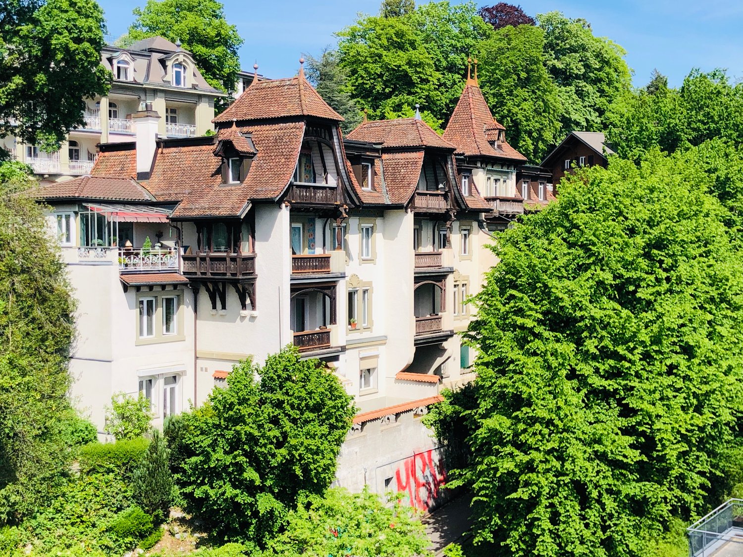 a 3 story building, white painted exterior, brown roof, balconies