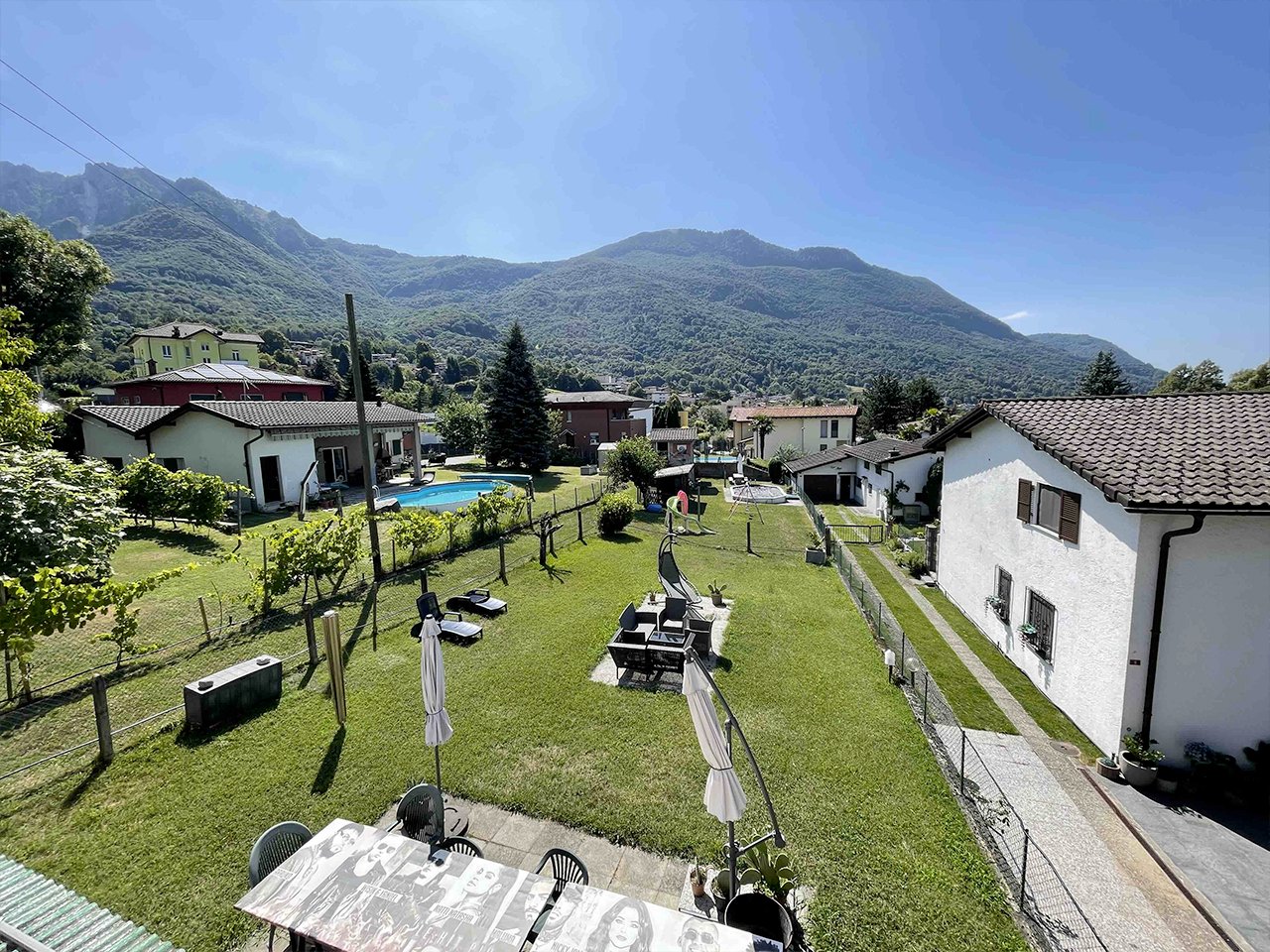 Complex of houses with swimming pool, garden area, and open view of the mountain.