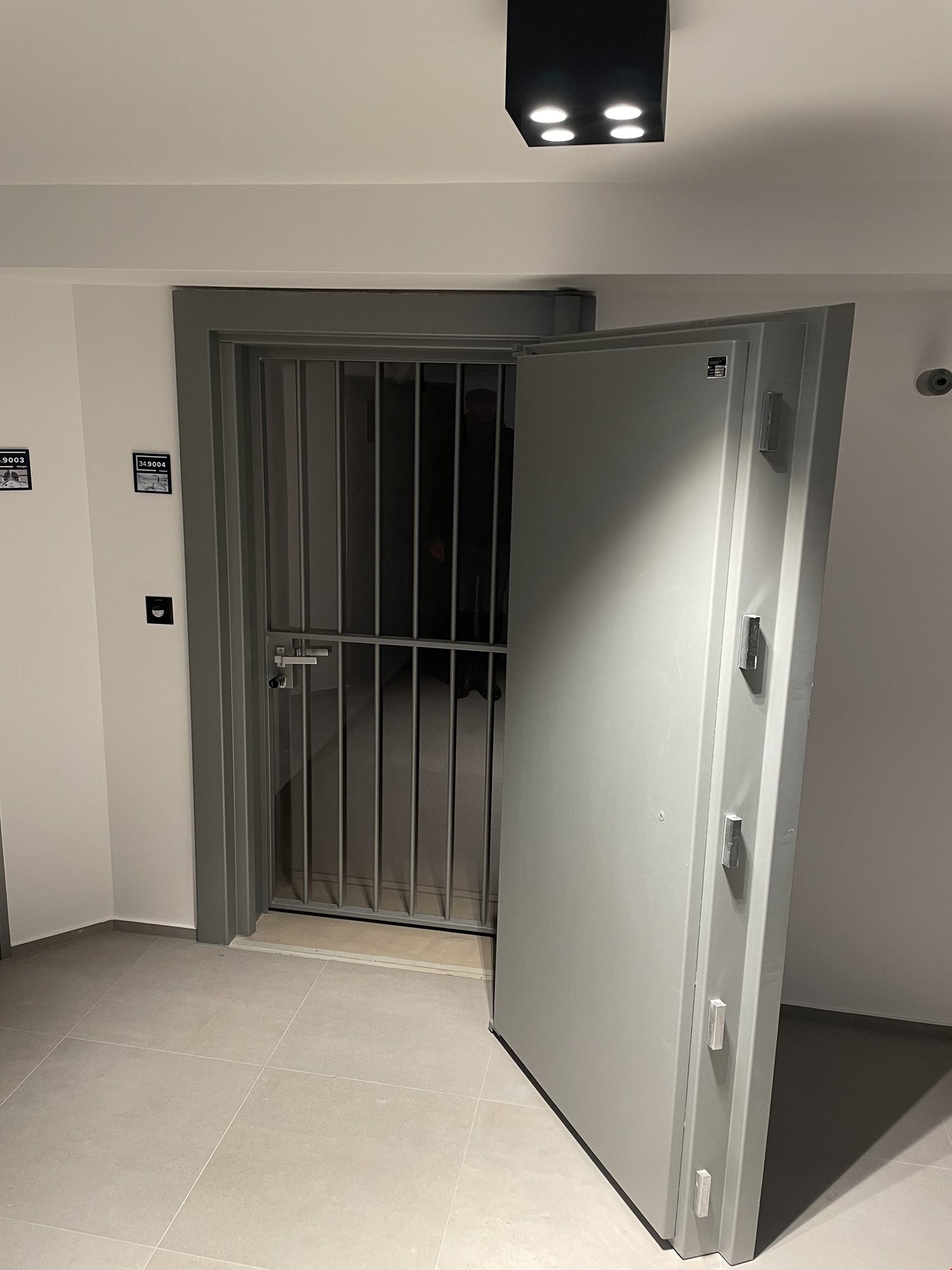 Entrance with metal gate, small hallway, tiled floor, and metal ceiling fixtures.