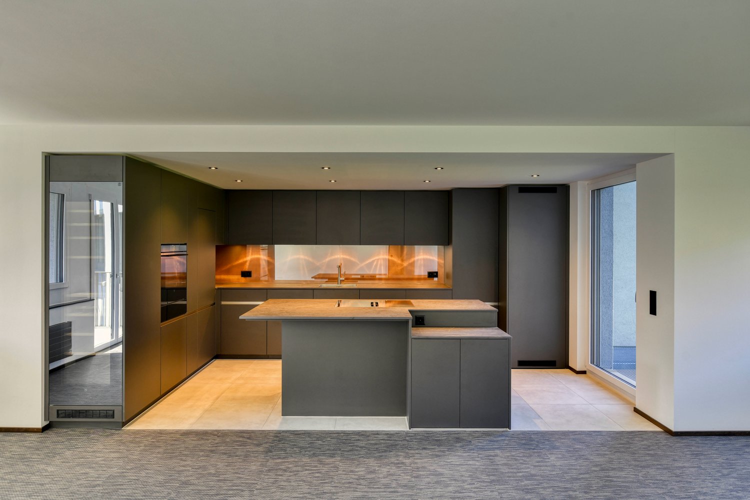 modern kitchen with island, gray cabinets, wooden countertops, built-in appliances, large windows