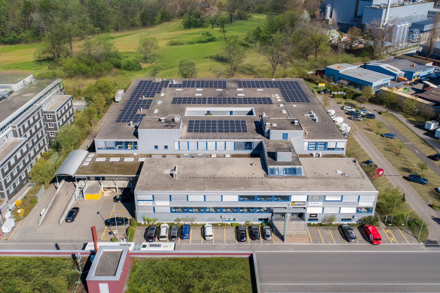 Industrial building, rooftop solar panels, multiple floors, large parking lot