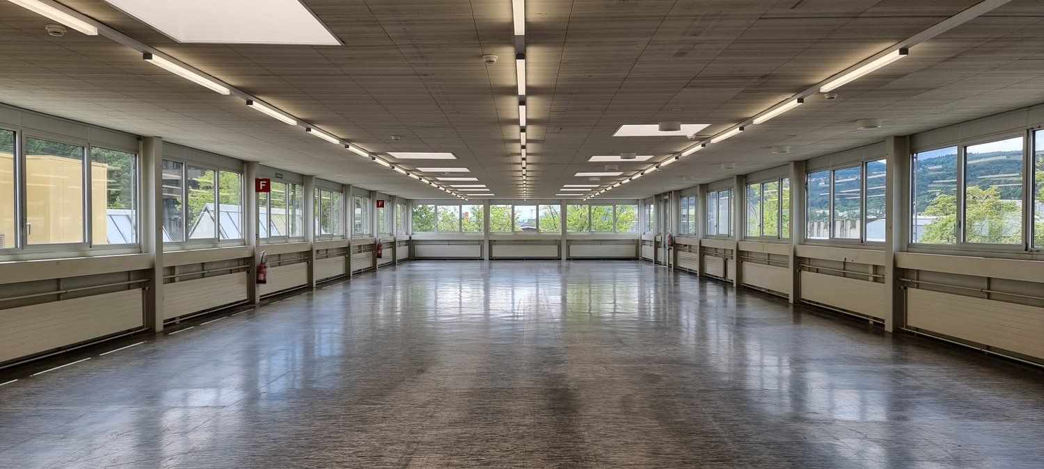 long hallway with large windows, fluorescent ceiling lights, fire extinguishers, shiny tiled floor