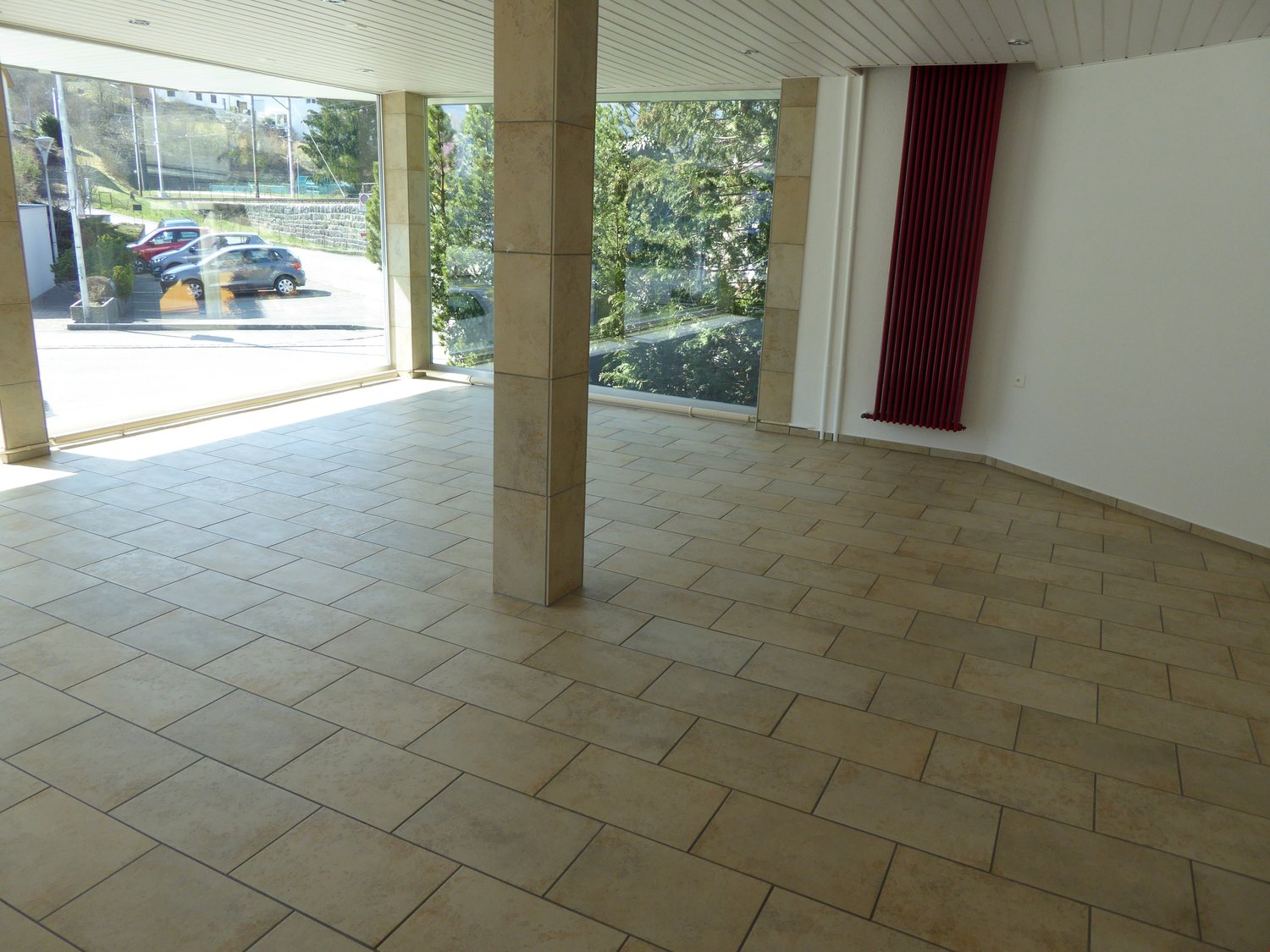 large empty room with large windows, tiled floor, large pillar, white walls
