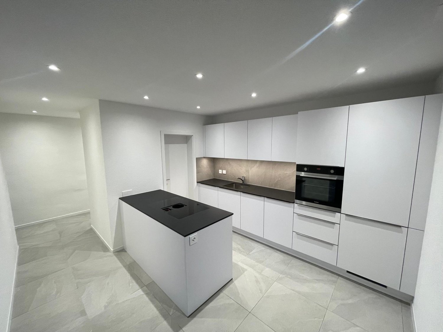 modern kitchen, white cabinets, black countertops, stainless steel appliances, tiled flooring