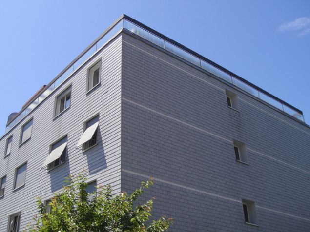 4 story building, brick facade, glass windows, glass balcony on top floor