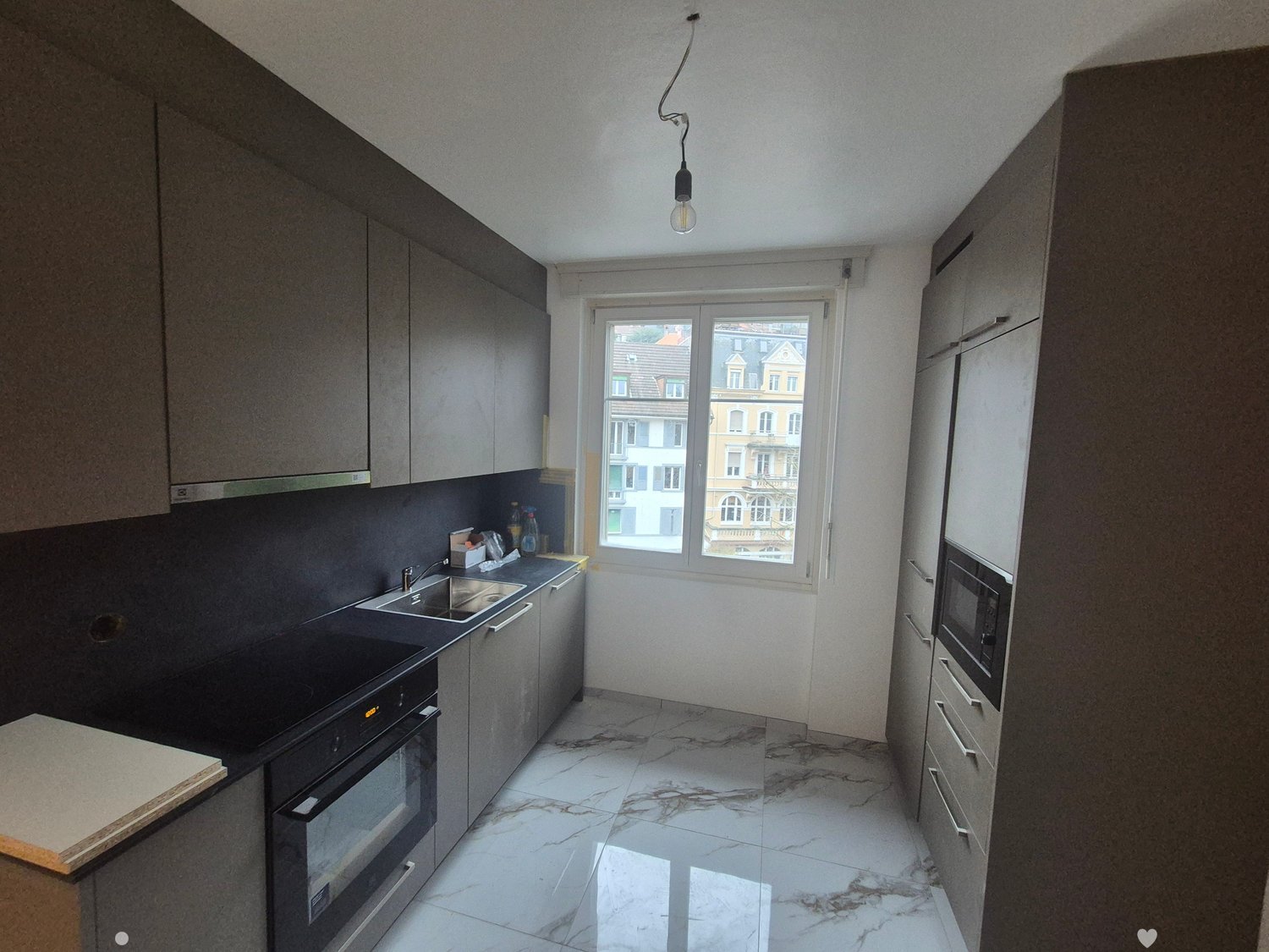 modern kitchen with black and grey colors, electric stove, sink, cabinets, marbled flooring