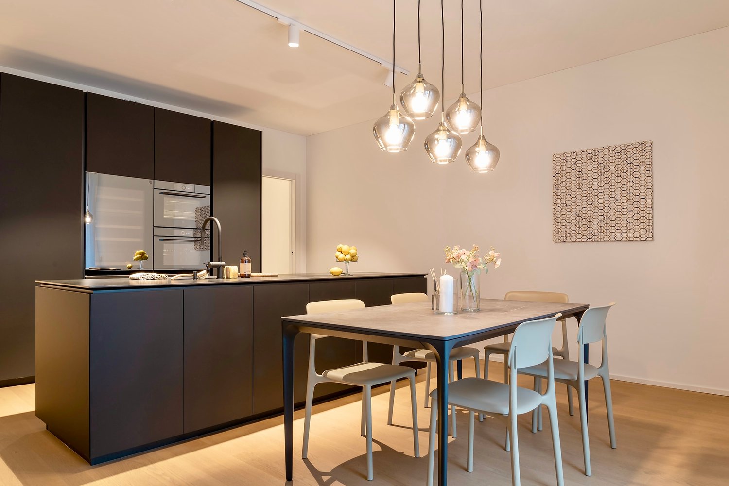 modern kitchen with central island, stainless steel appliances, contemporary dining area with table and chairs, decorative elements
