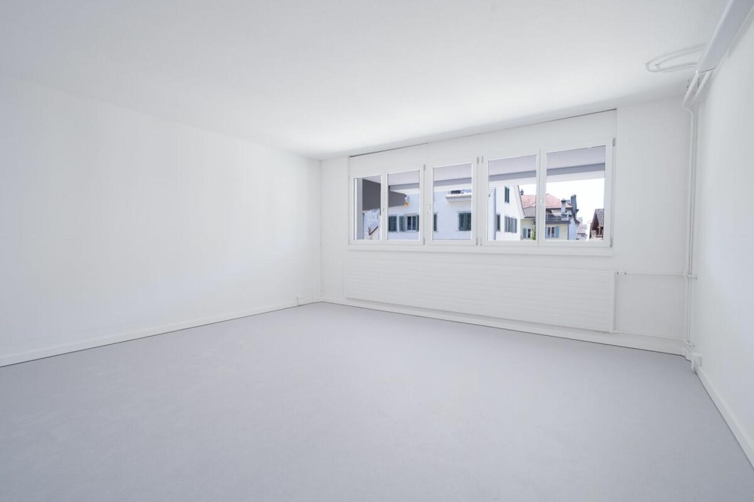 white walls, white floor, large windows, modern radiator, view to street