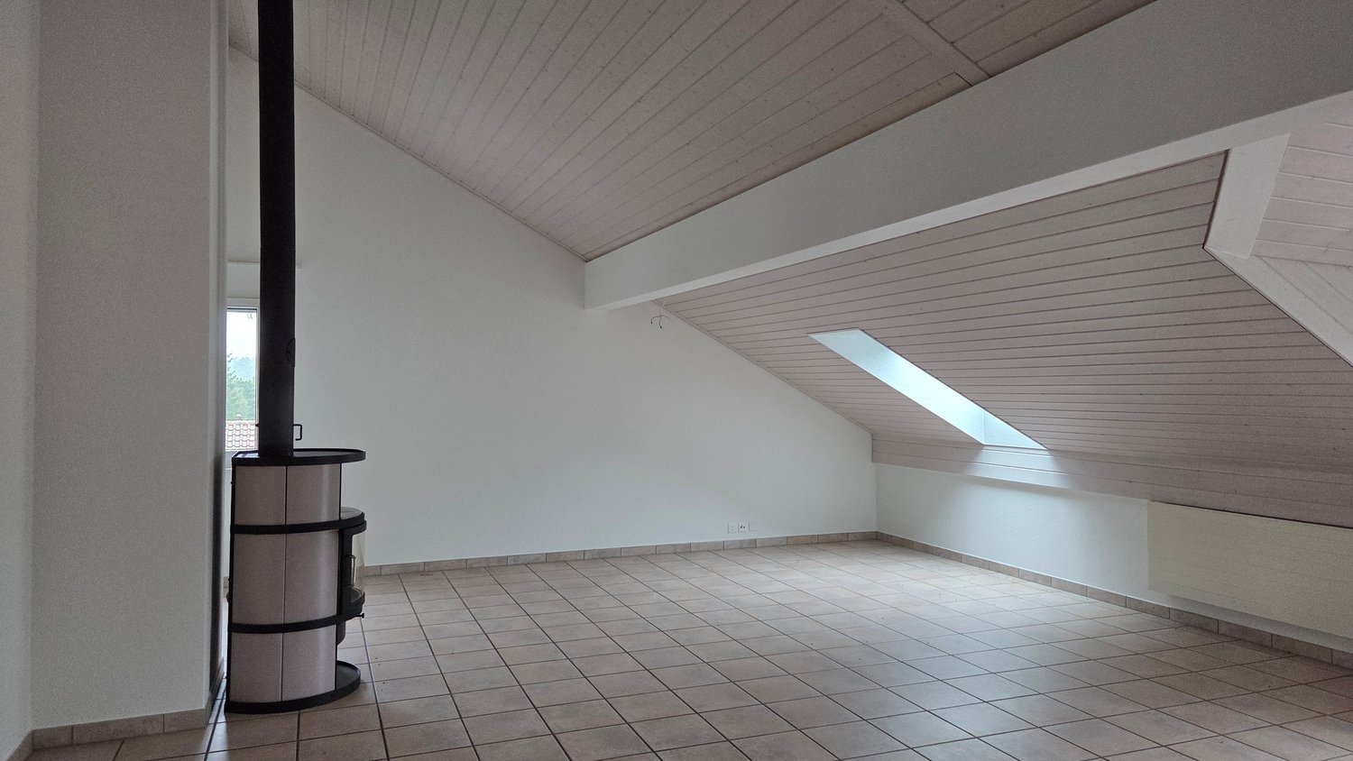 empty room with ceiling and floor made of tiles, white walls, one window and a chimney