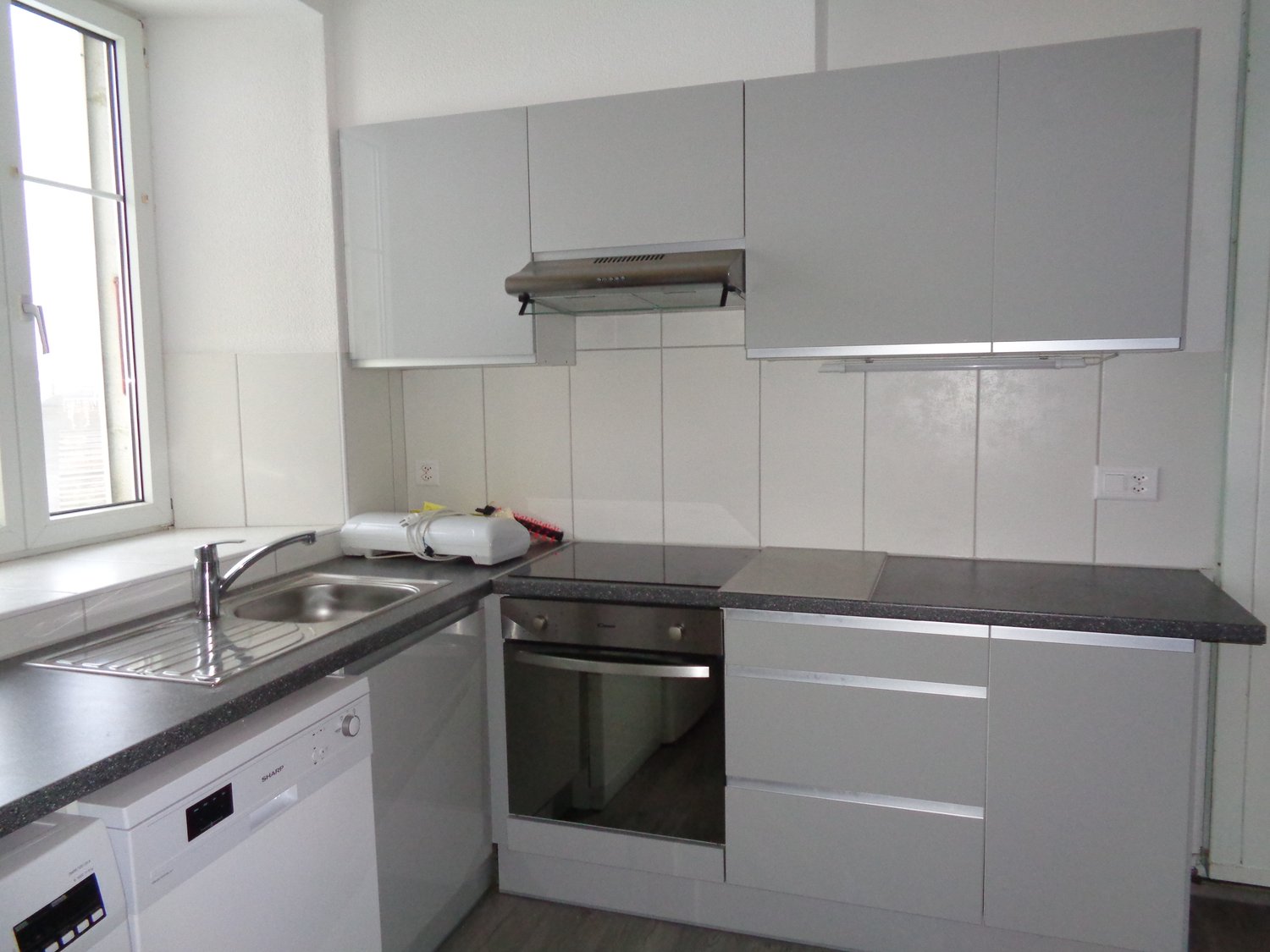 White kitchen with stainless steel sink, countertop, integrated dishwasher, built-in oven, built-in microwave, and cabinets