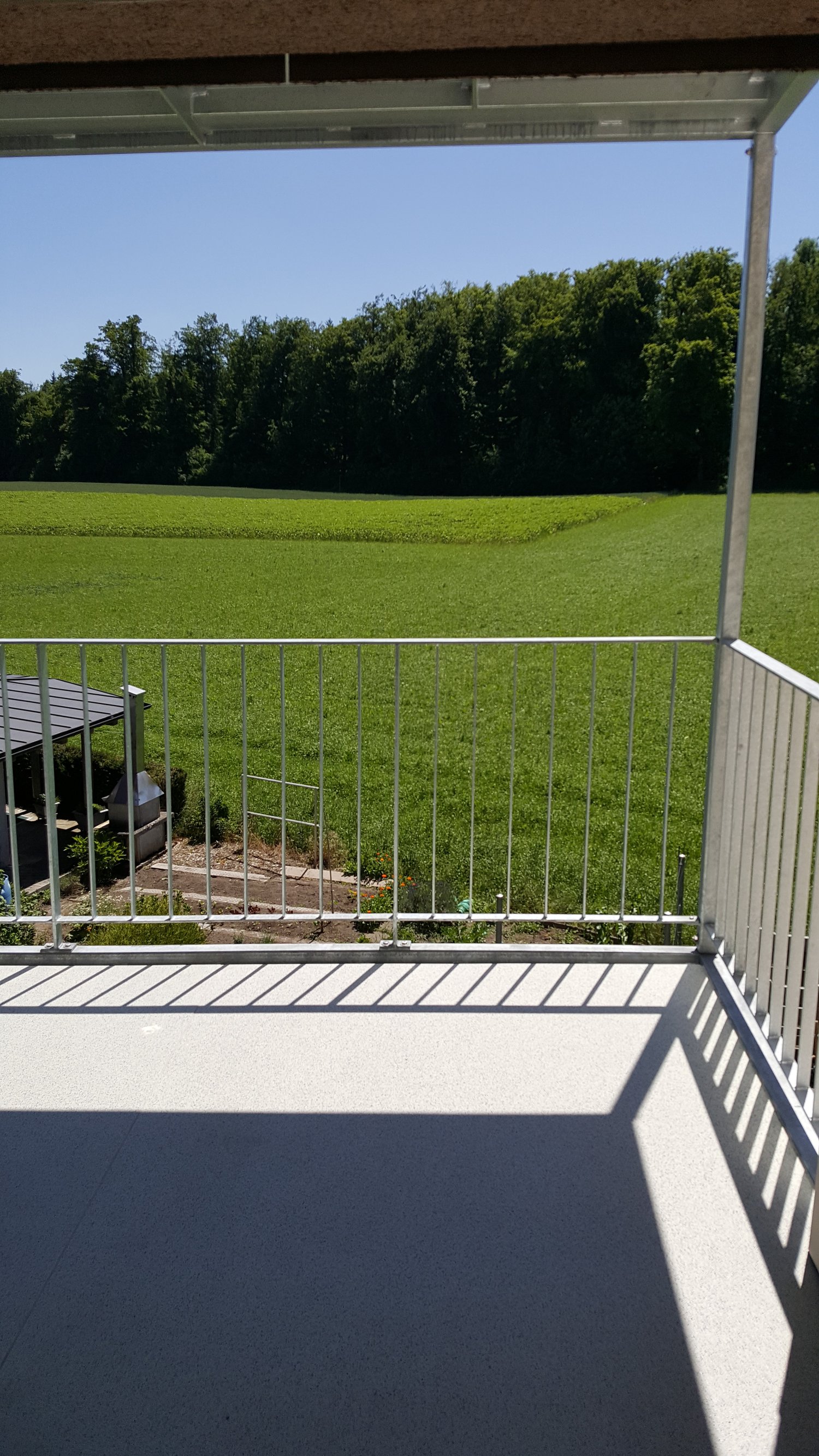 balcony with white railings, floor, open view of field, some trees