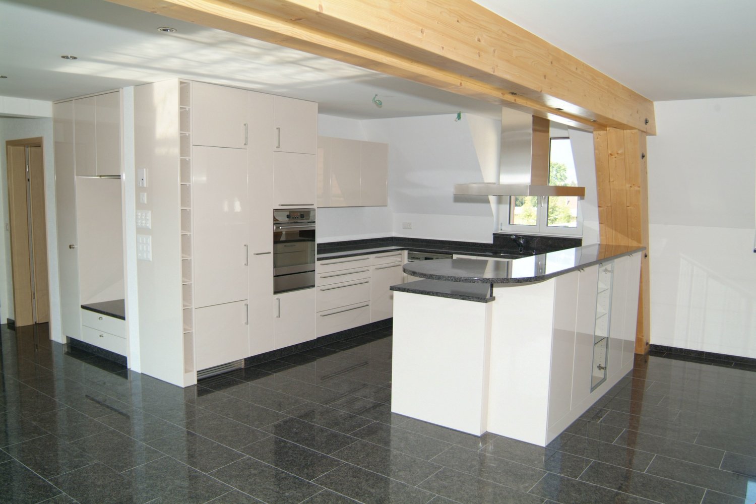 open kitchen with island, granite counter top, built-in appliances, white cabinets, tiled floor, open to living area