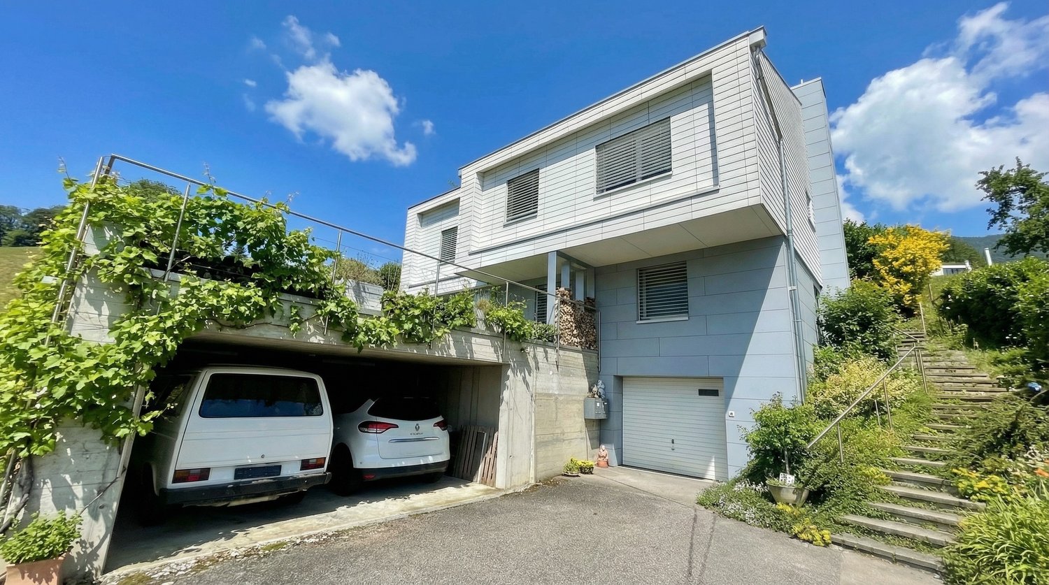white 2 story house, garage for 2 cars, steps to the entrance, covered parking area, plants on the wall