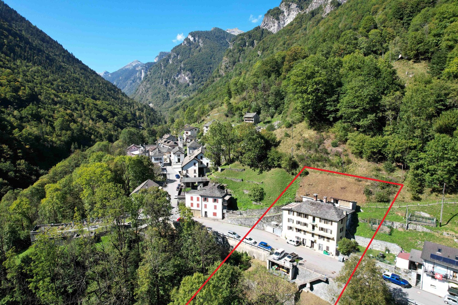 Stone building in a mountainous area, white facade, located on the edge of the road, several trees